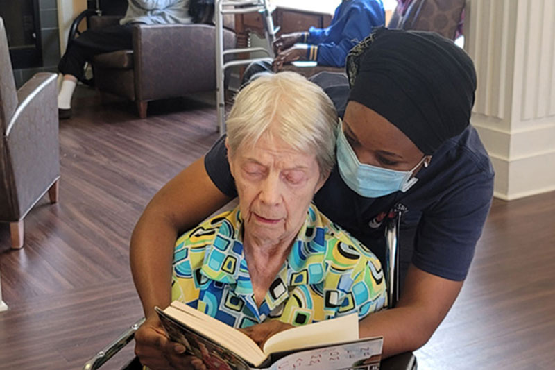 Staff member helping resident read at Superior Residences of Brandon